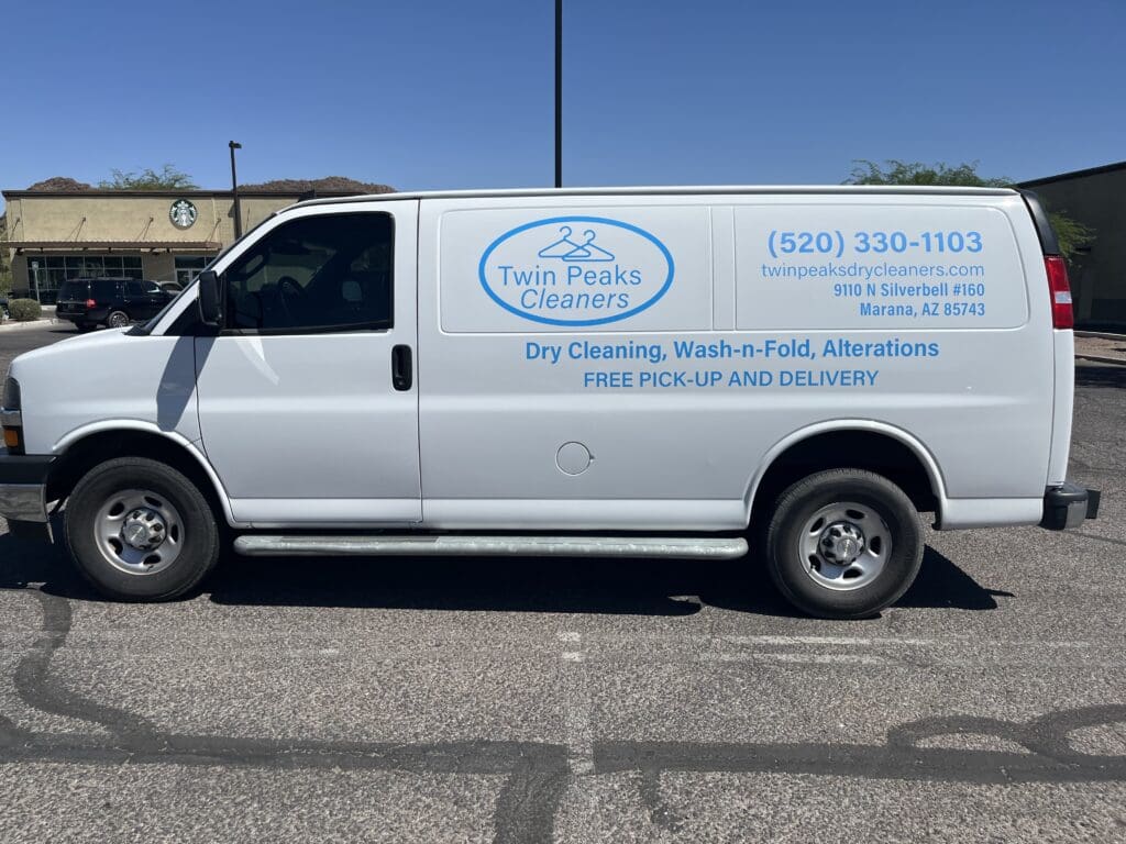 White delivery van parked in a lot, displaying "Twin Peaks Cleaners" branding and contact information for dry cleaning, wash-n-fold, alterations, and free pick-up and delivery services.